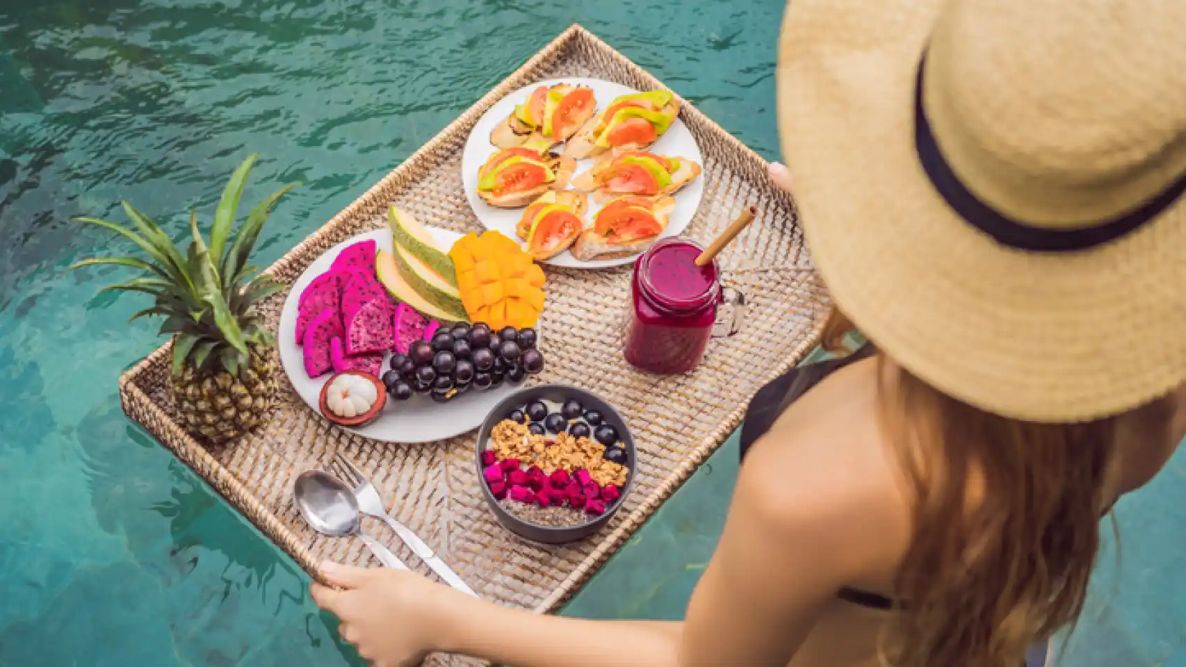 chica con bandeja de comida tropical en la piscina